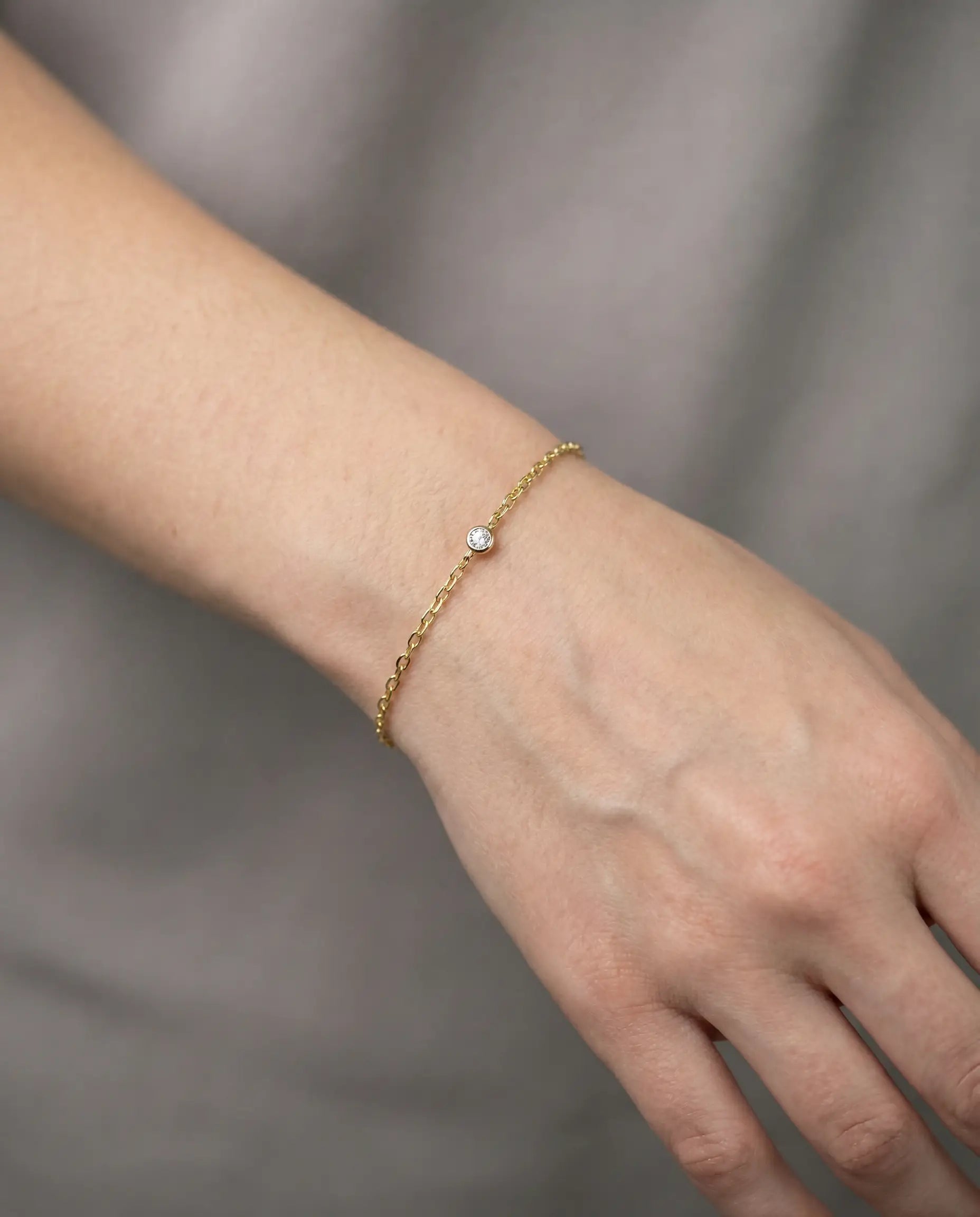 Srebrna narukvica sa tankim lančićem i jednim cirkonom u disk postavci zuta pozlata